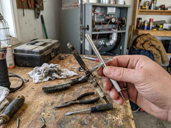 Oxidised flame sensor rod beside a clean replacement