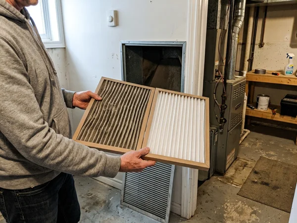 Loaded furnace filter beside a clean replacement